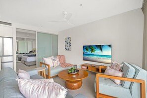 Ein modernes Wohnzimmer mit einem Flachbildfernseher, einem runden Couchtisch und einem Sofa.
