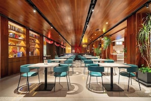 A restaurant with wooden paneling, teal chairs, and tables. - Huidong Business Hotel (Linyi)