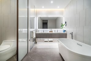 A modern bathroom with a glass-enclosed shower, a freestanding bathtub, and a vanity with a large mirror. - Huidong Business Hotel (Linyi)