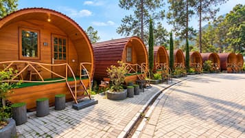 Una hilera de alojamientos tipo cápsula de madera, con escaleras exteriores y zonas de estar al aire libre.