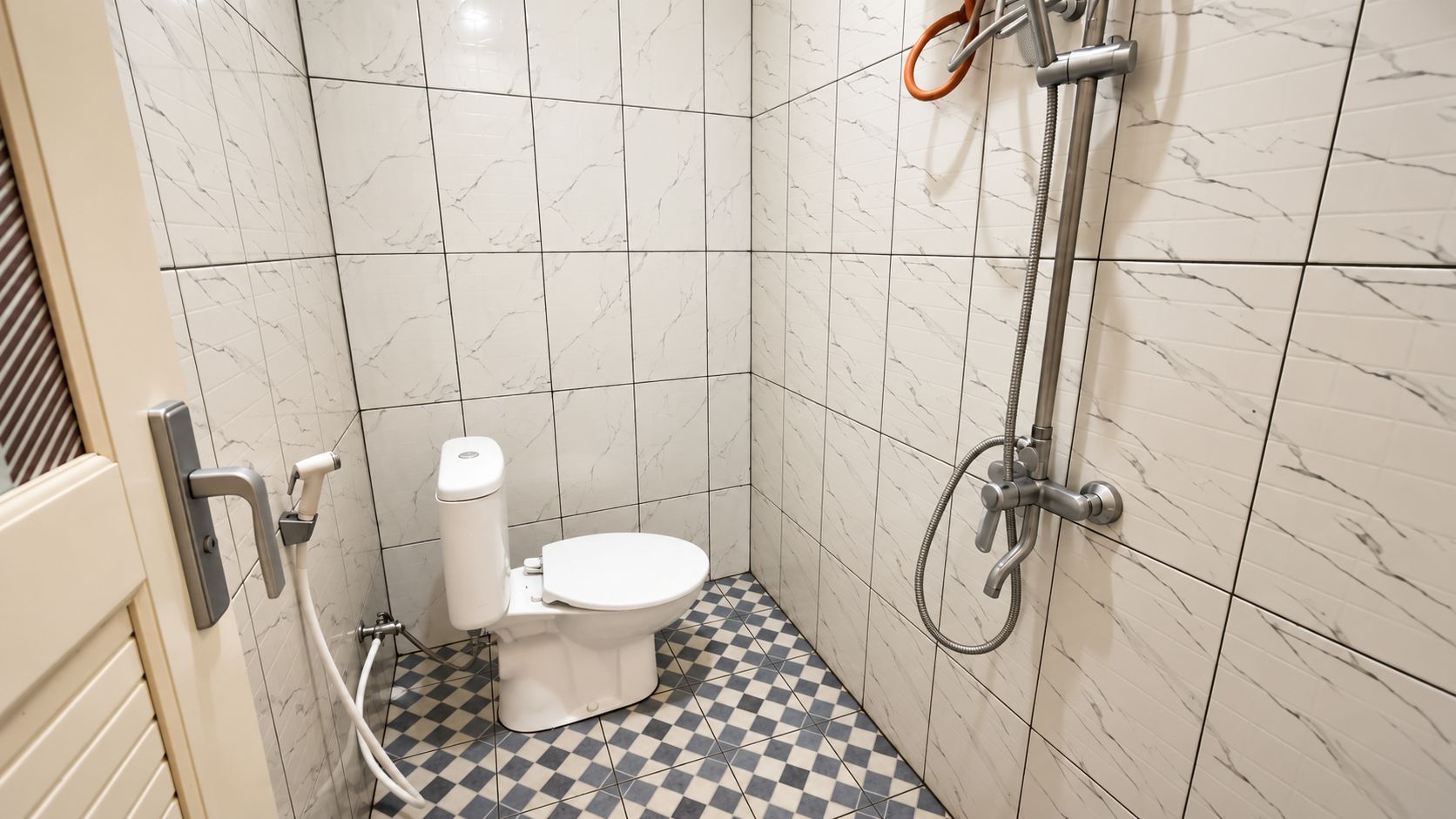 A bathroom with a toilet, a shower, and a checkered floor.