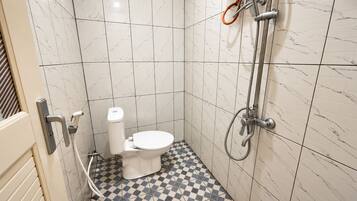 A bathroom with a toilet, a shower, and a checkered floor.