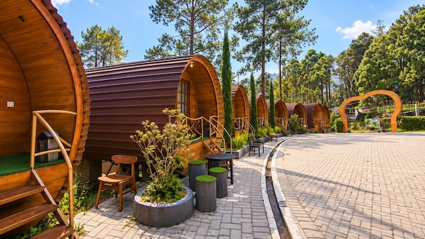 A row of wooden cabins with outdoor seating and a paved walkway.
