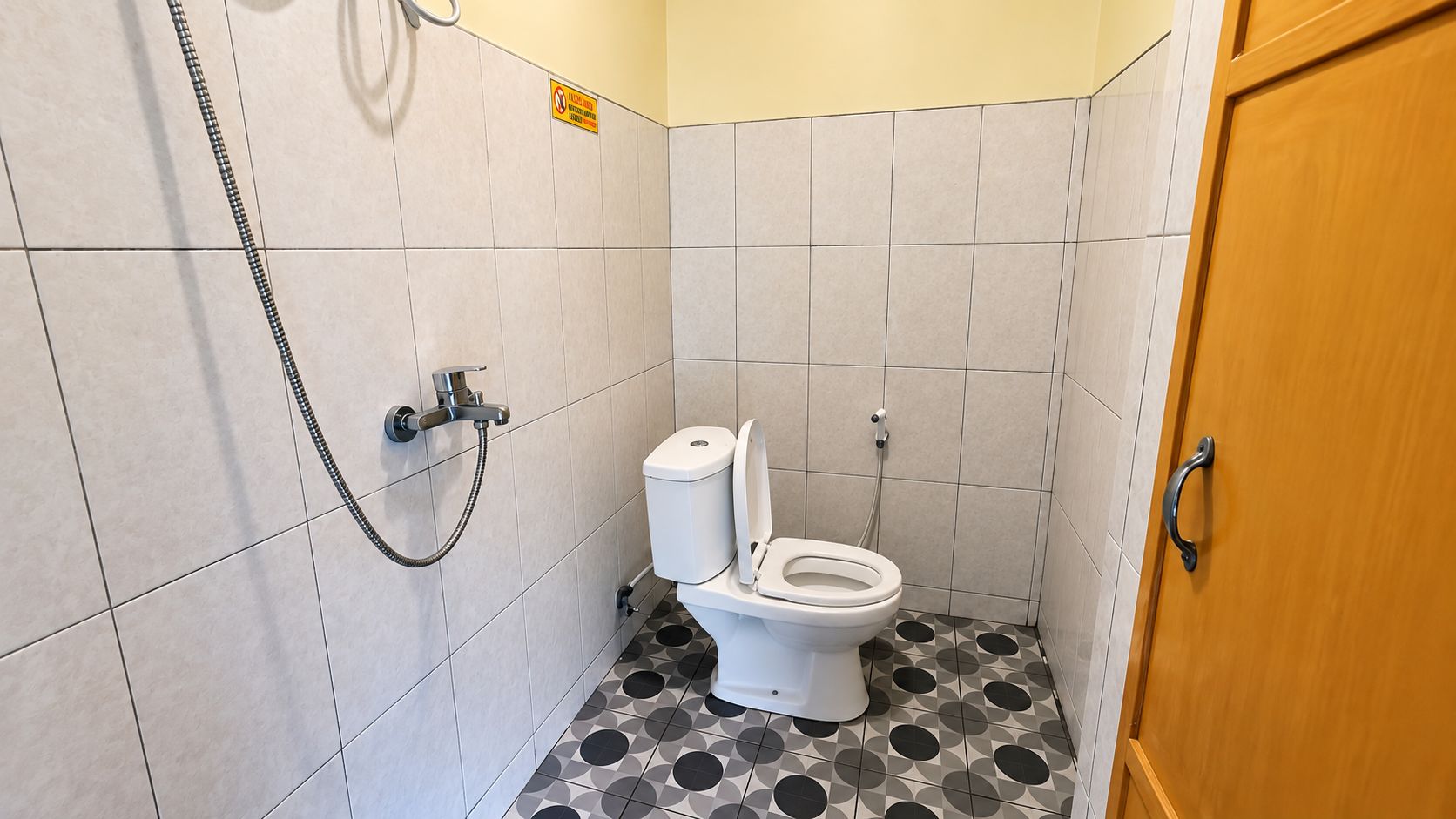 A small bathroom with a toilet, a shower, and a door.