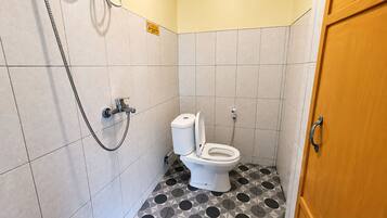 A small bathroom with a toilet, a shower, and a door.