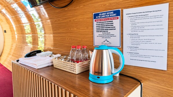 A reception desk with a kettle, bottled water, and a check-out sign.