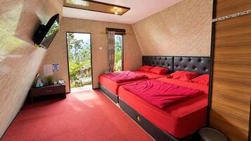 A bedroom with a large bed, a flat-screen TV, a desk, and a view of the outdoors.