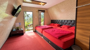 A bedroom with a large bed, a flat-screen TV, a desk, and a view of the outdoors.