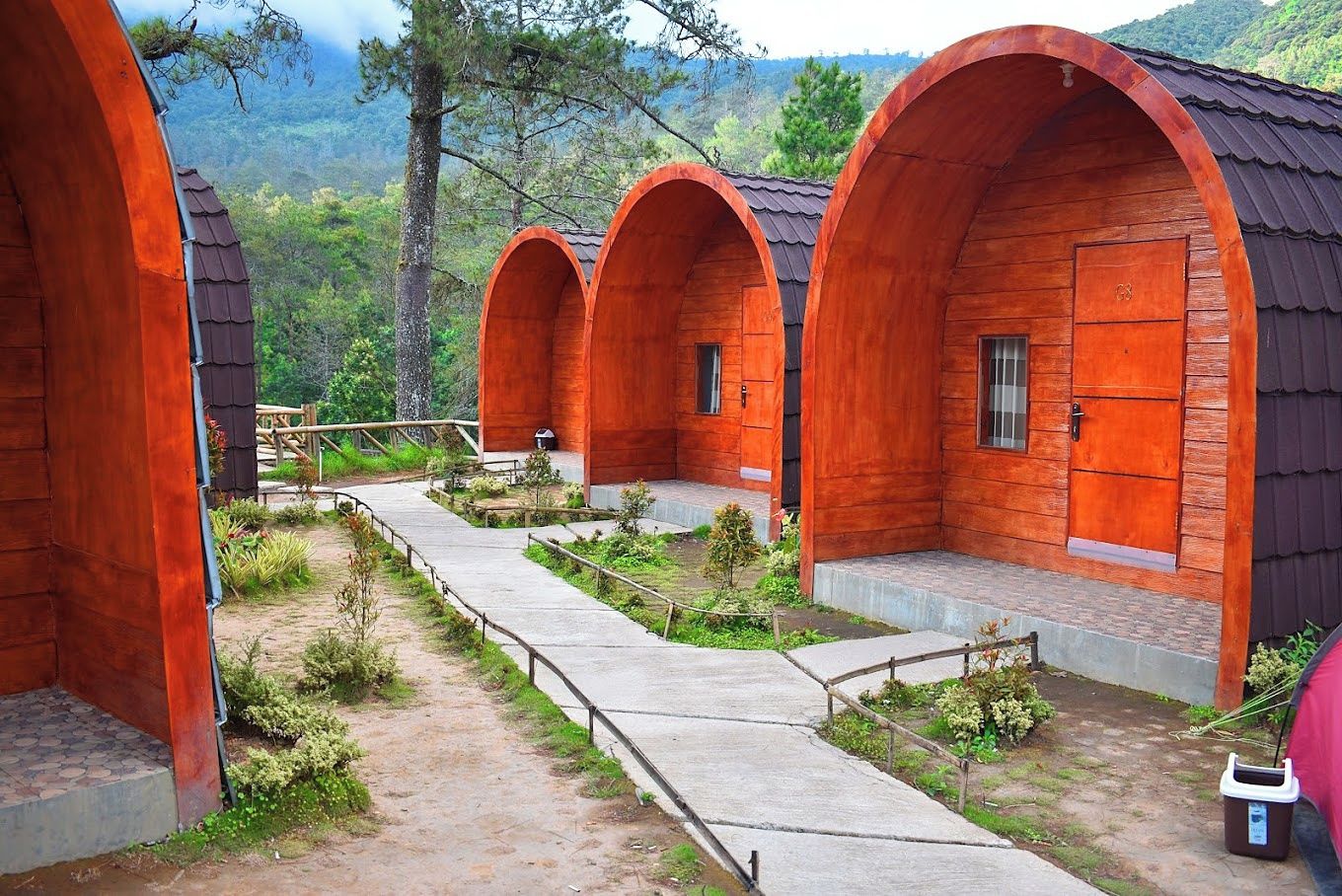 A row of wooden cabins with a concrete pathway between them.