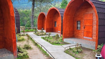 A row of wooden cabins with a concrete pathway between them.
