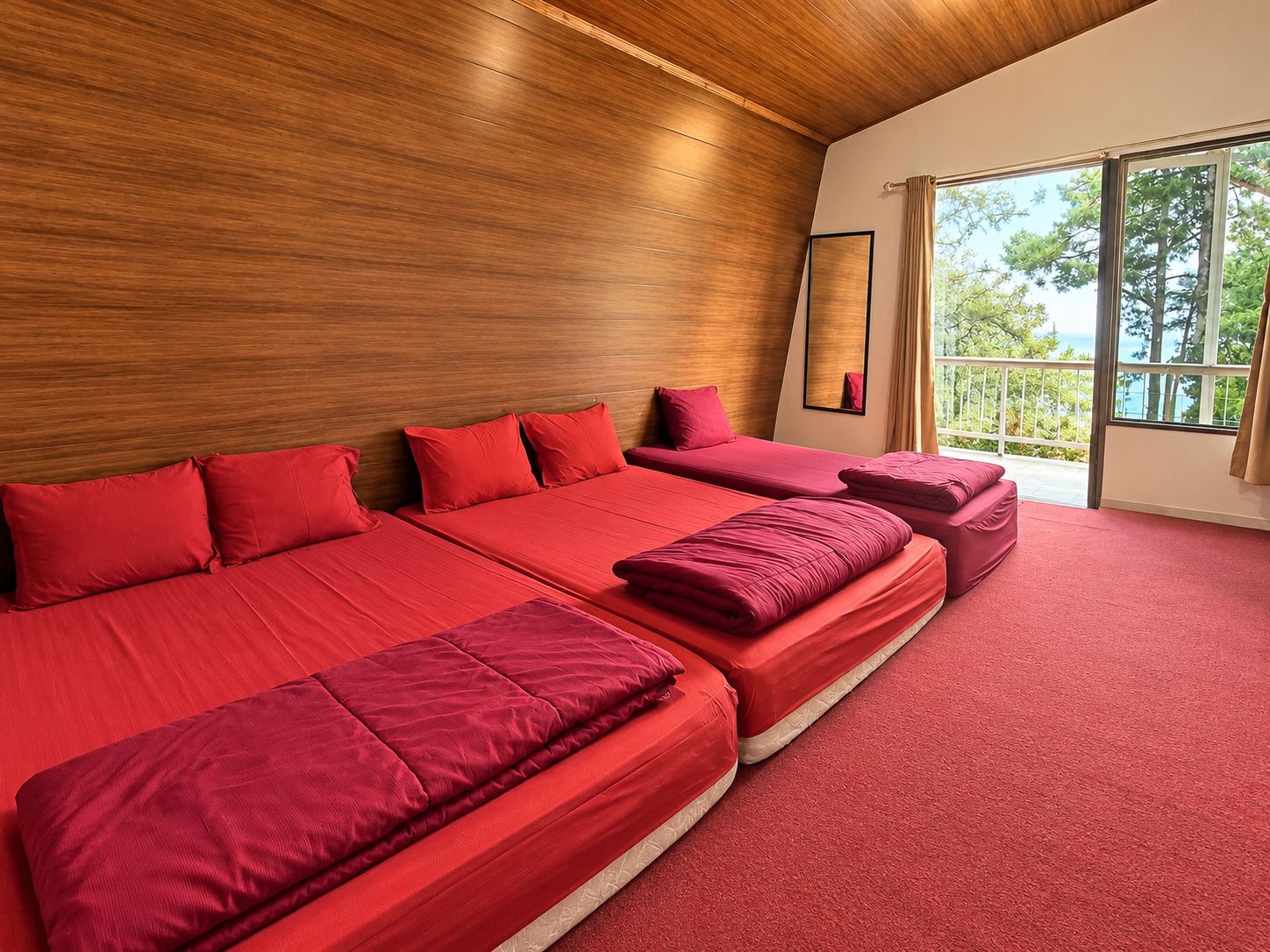 Une chambre d’hôtel avec un plafond en bois, de grandes fenêtres et une moquette rouge.