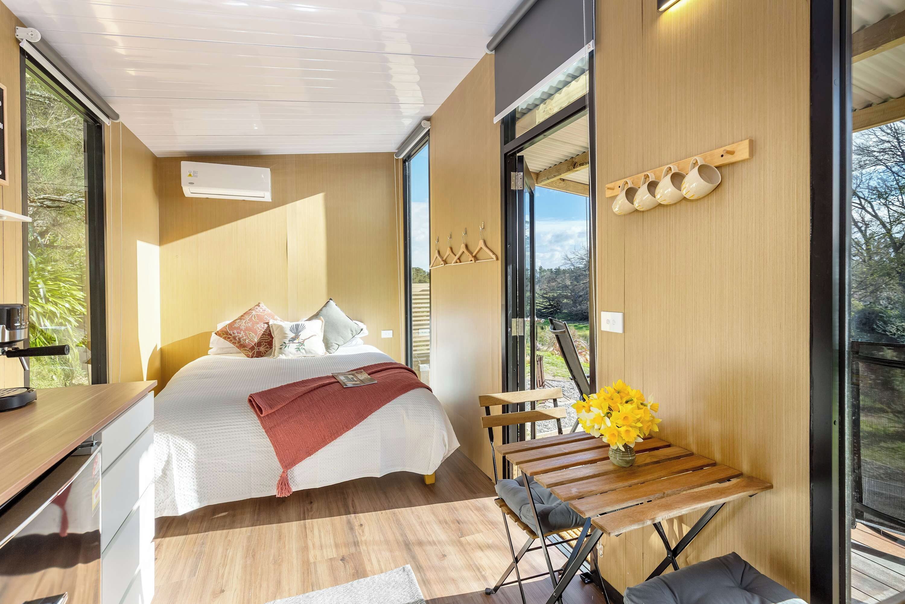 A modern bedroom with a bed, bedside table, and a view of the outdoors.