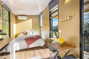 A modern bedroom with a bed, bedside table, and a view of the outdoors. - Papa Ora Healthy Earth Stays X by Tiny Away (Rangitūmau)