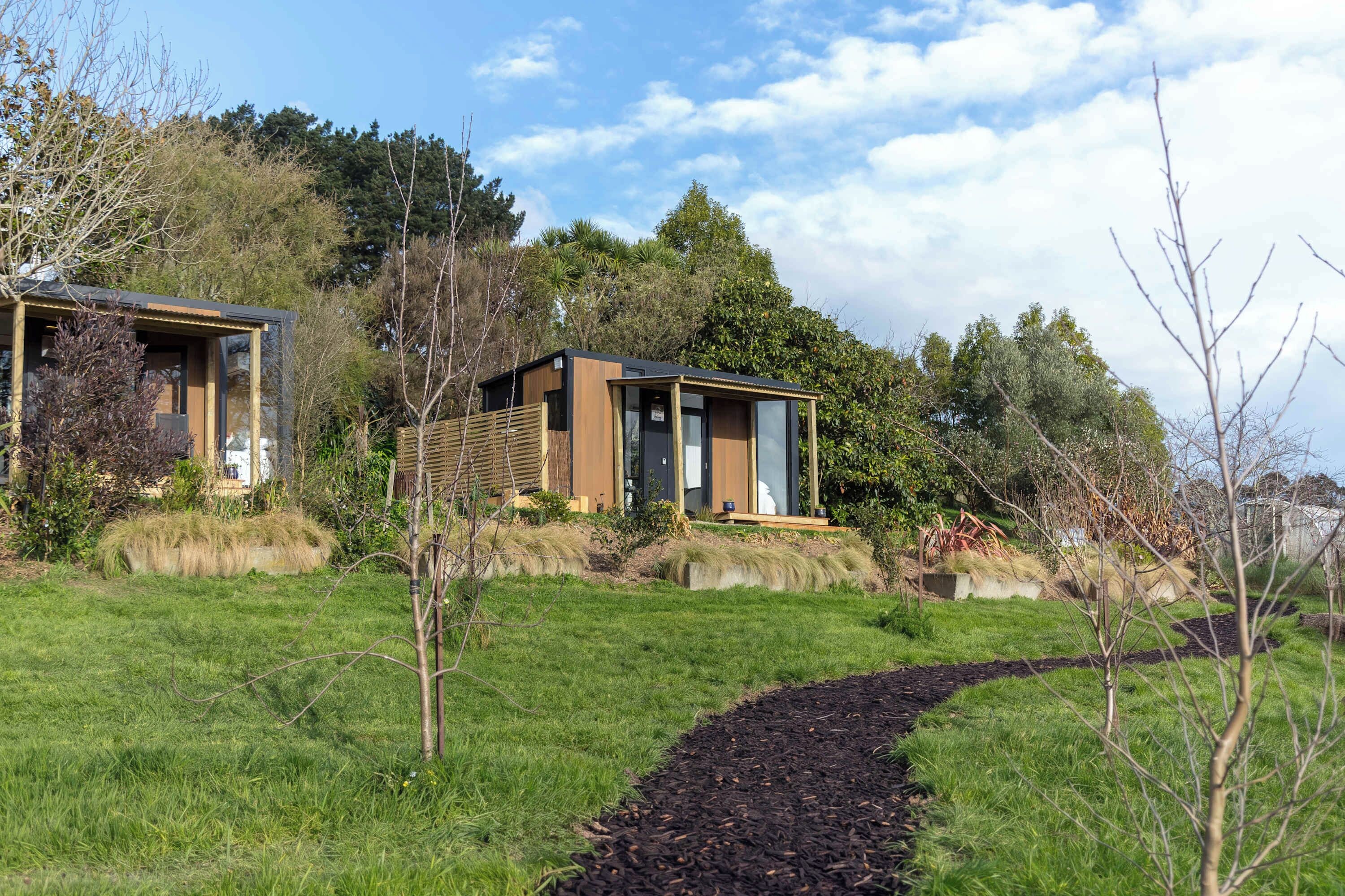A modern house with a wooden deck and a pathway leading to the entrance.