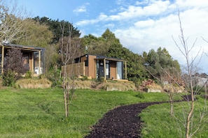 A modern house with a wooden deck and a pathway leading to the entrance. - Papa Ora Healthy Earth Stays X by Tiny Away (Rangitūmau)