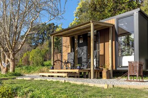 A modern outdoor seating area with a wooden pergola, a black chair, and a small table.