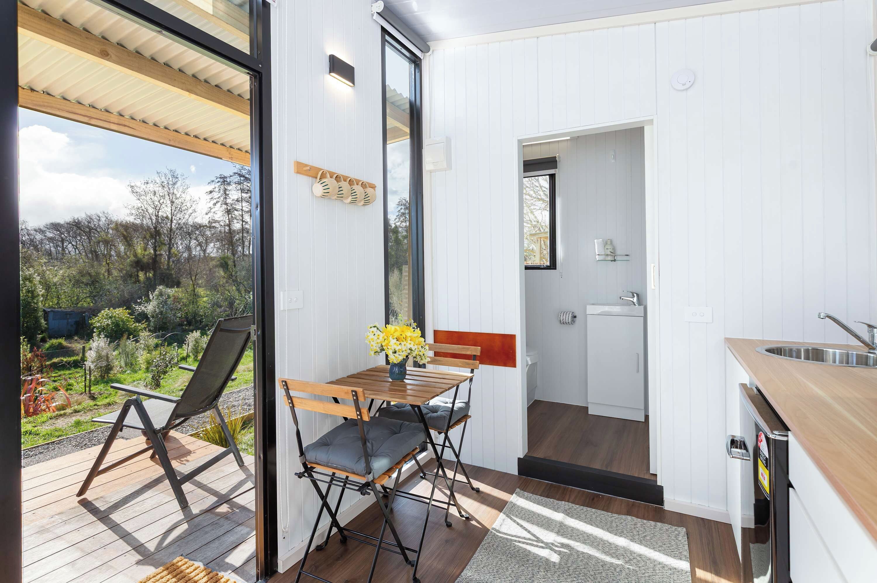 A compact kitchen with a sink, a dining area with a table and chairs, and a view of the outdoors.