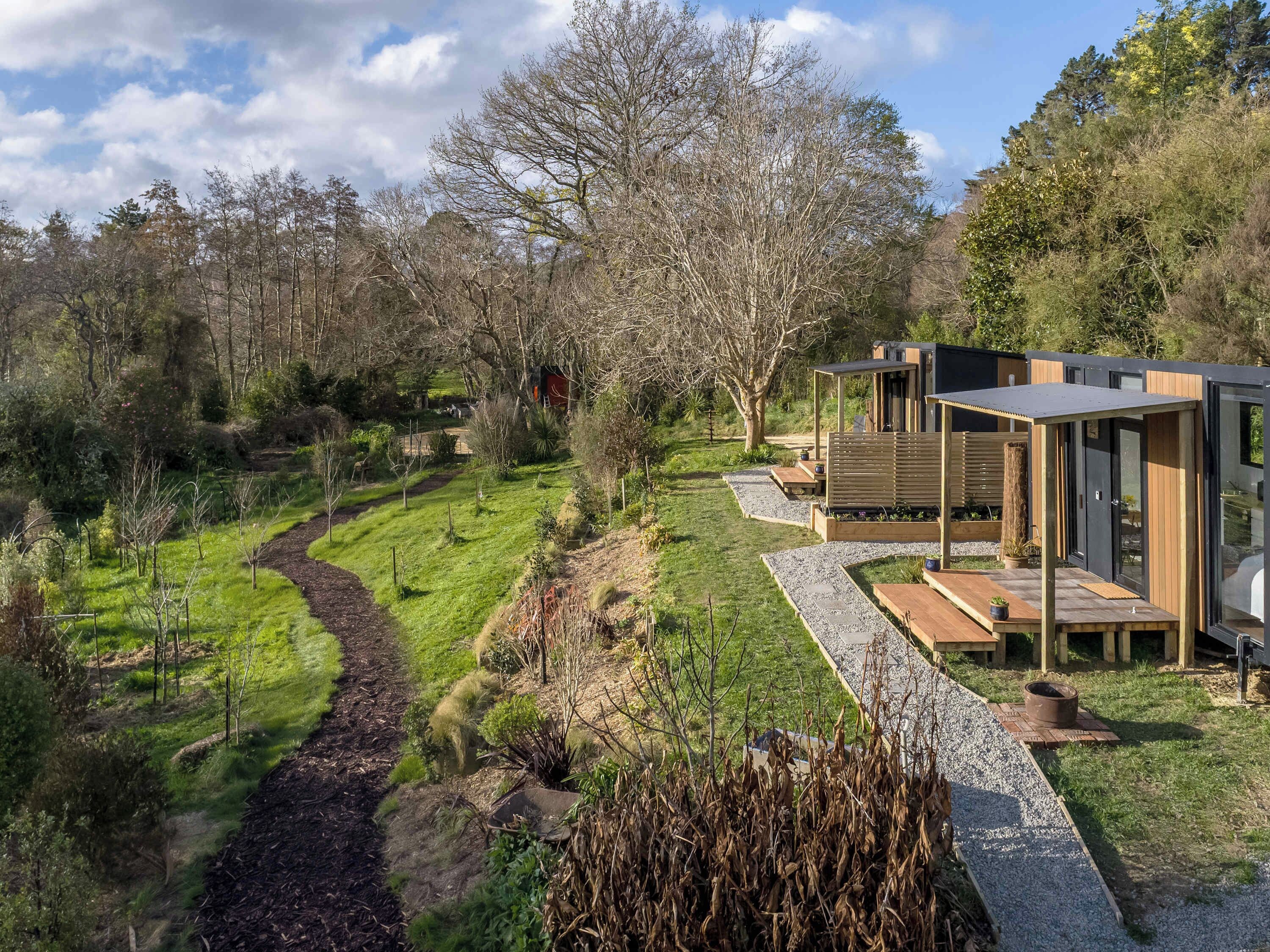 Een modern buitengebied met een pad, een houten terras en een gebouw met grote ramen.