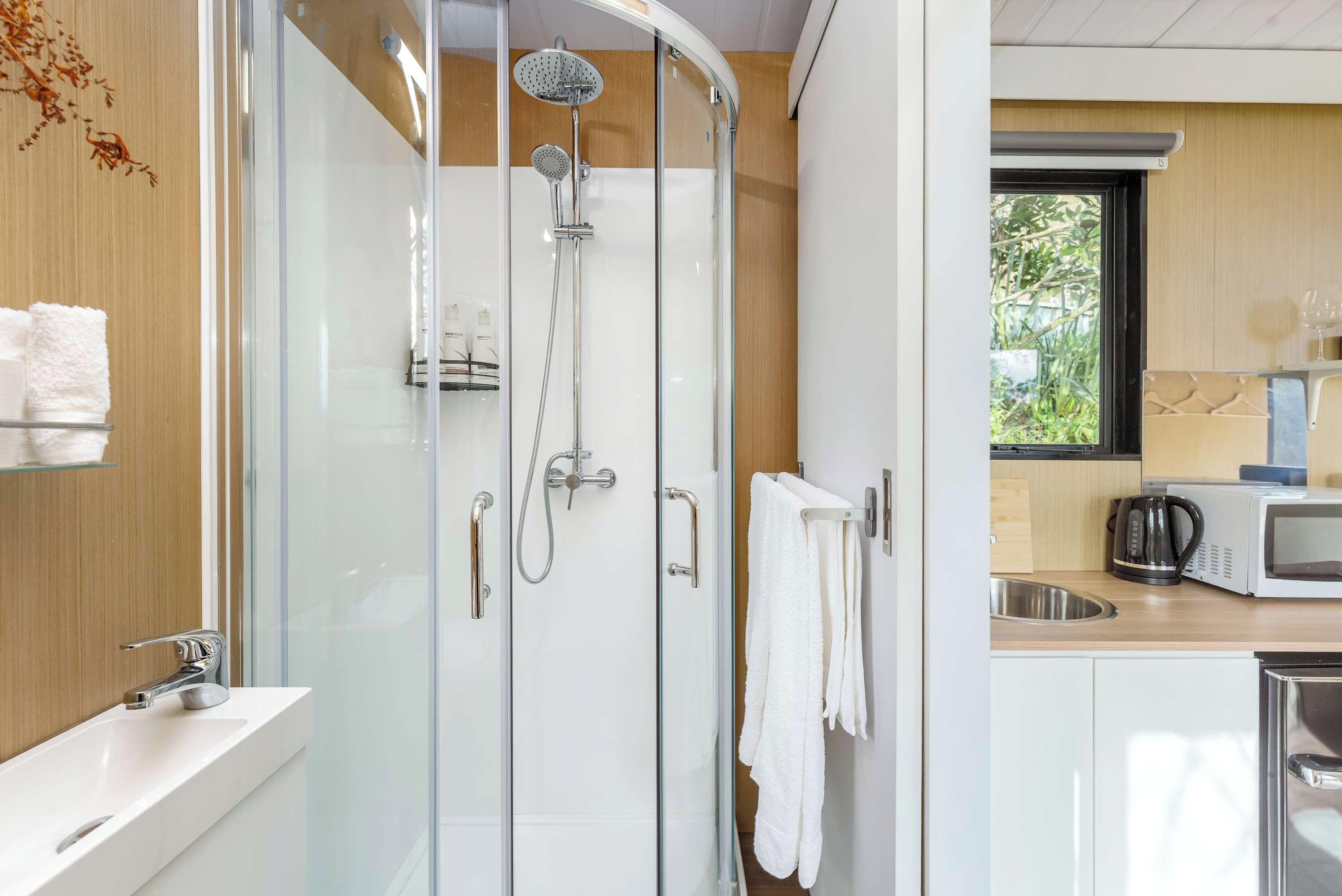 A modern bathroom with a glass-enclosed shower, a white sink, and a towel rack.