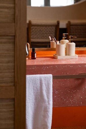 A bathroom with a wooden chair, a towel, and toiletries on a counter. - Gea Perla Serifos (Serifos)