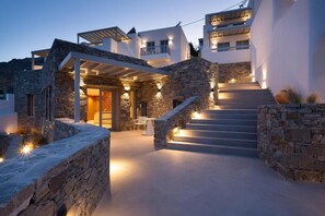 A modern building with multiple levels, stone walls, and a staircase leading to the upper floors. - Gea Perla Serifos (Serifos)