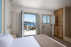 A hotel room with a bed, a door leading to a balcony, and a view of the sea. - Gea Perla Serifos (Serifos)