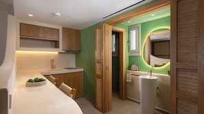A modern kitchen with a built-in island, wooden cabinetry, and a green accent wall. - Gea Perla Serifos (Serifos)