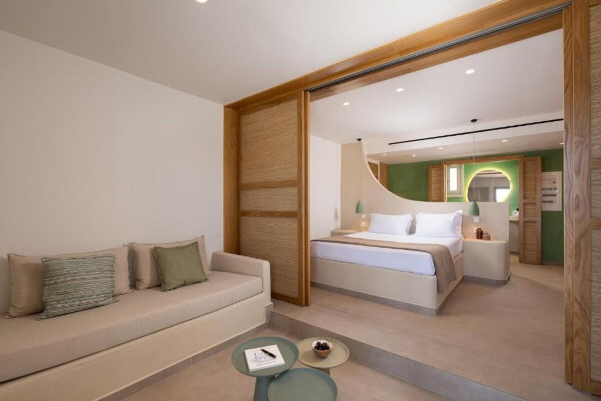 A modern hotel room with a sofa, a bed, a small table, and a mirror.