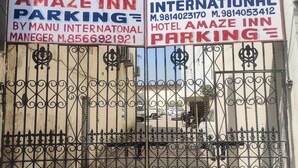 A gated entrance with signs for Hotel Amaze Inn and Manu International, indicating parking availability. - Hotel Amaze Inn (Amritsar)