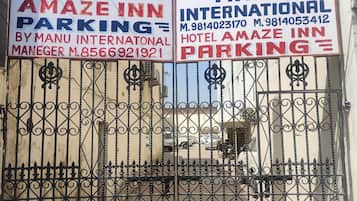 Portão fechado com placas indicando Hotel Amaze Inn e Manu International, mostrando a disponibilidade de estacionamento.