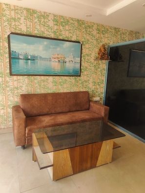 Uma sala de estar com sofá, mesa de centro e televisão na parede.