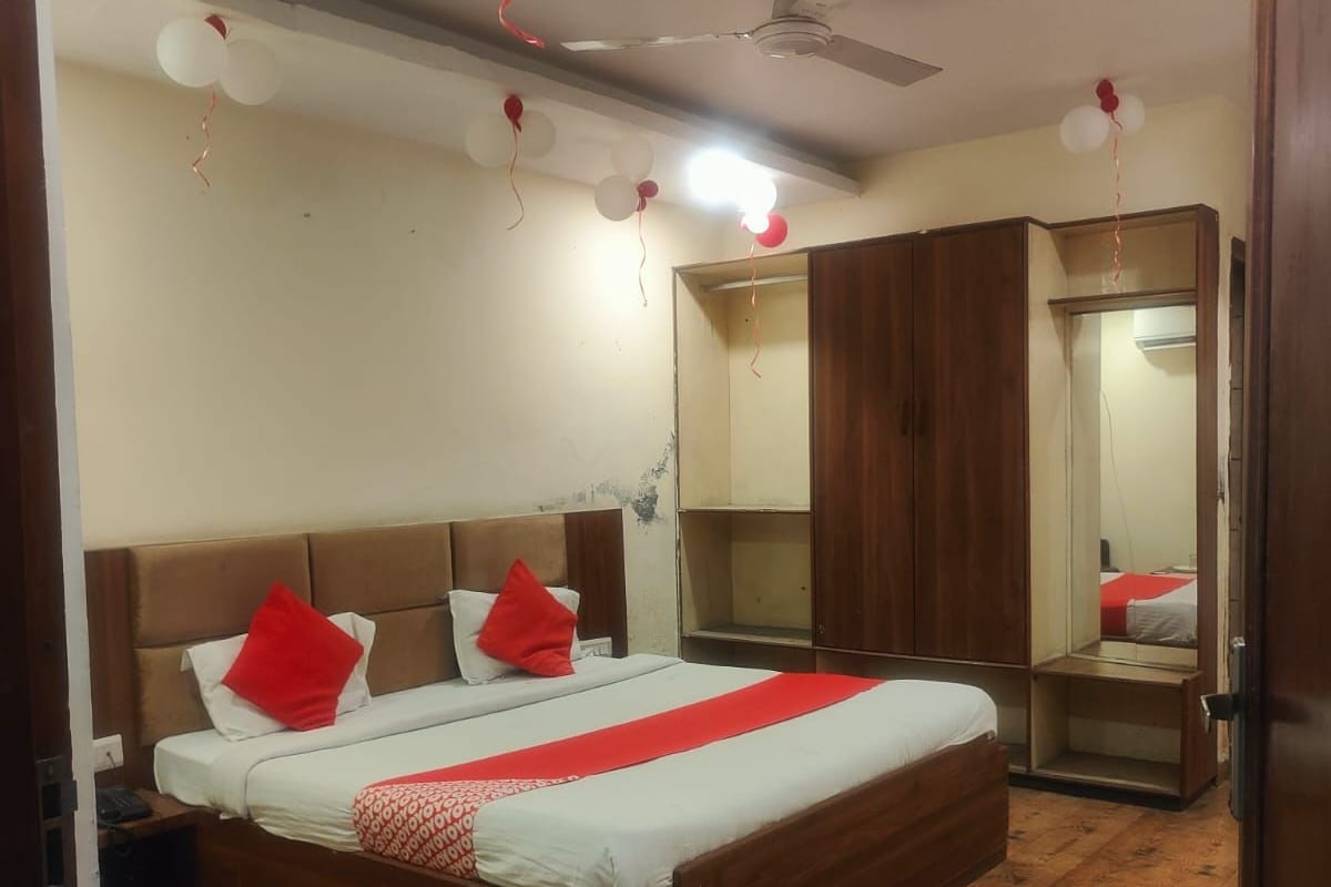 Quarto com cama grande, piso de madeira, guarda-roupa e ventoinha no teto.