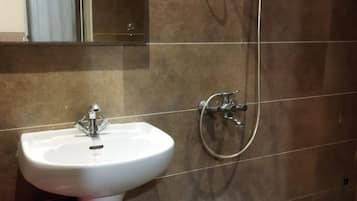 Un baño con un lavamanos blanco, un espejo y una ducha con cabezal de ducha de mano.