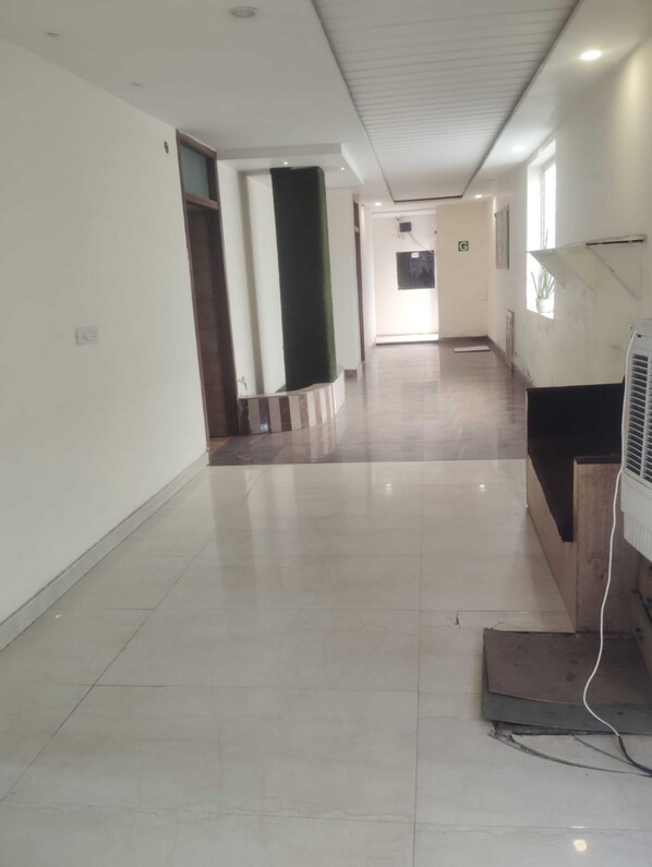 A hallway with a reception desk, a potted plant, and a tiled floor.