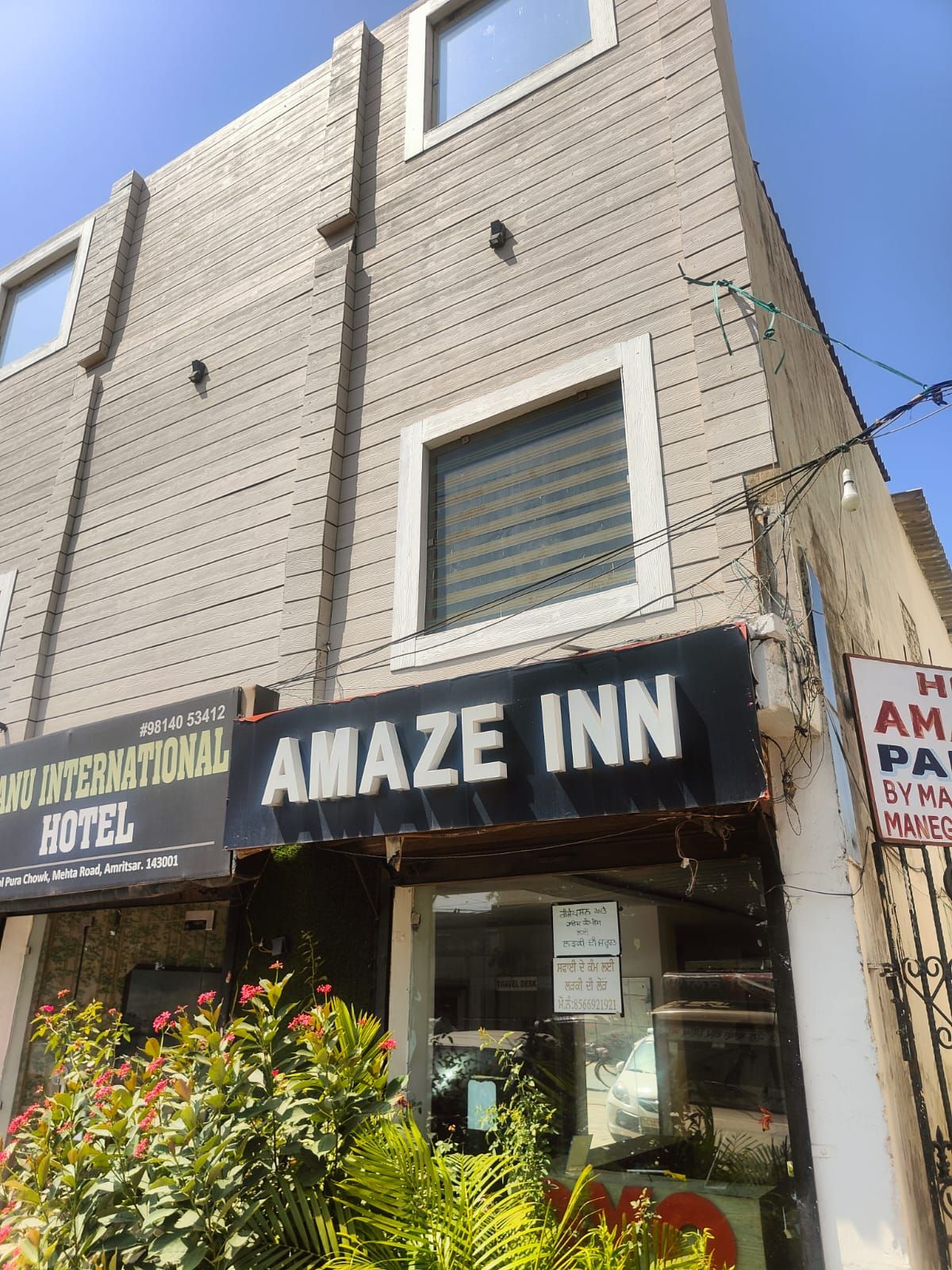 En byggnad med en skylt som visar texten ”AMAZE INN” och en annan skylt med texten ”MANU INTERNATIONAL HOTEL”.
