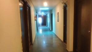 A corridor with doors on both sides, a ceiling light, and a door at the end. - Hotel Amaze Inn (Amritsar)