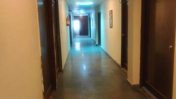 A corridor with doors on both sides, a ceiling light, and a door at the end.