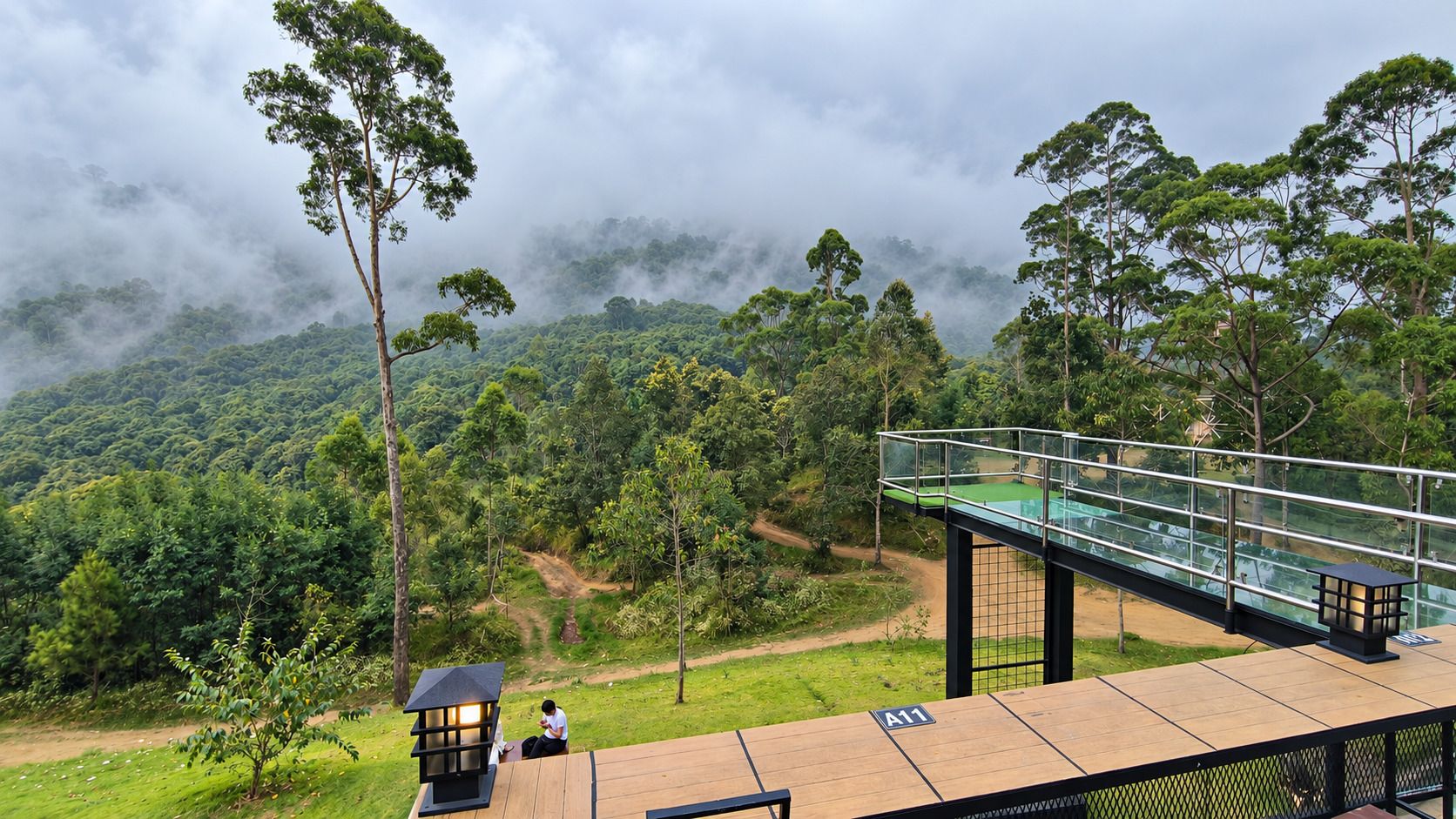 A glass bridge over a forested area with a clear path leading to a gazebo.