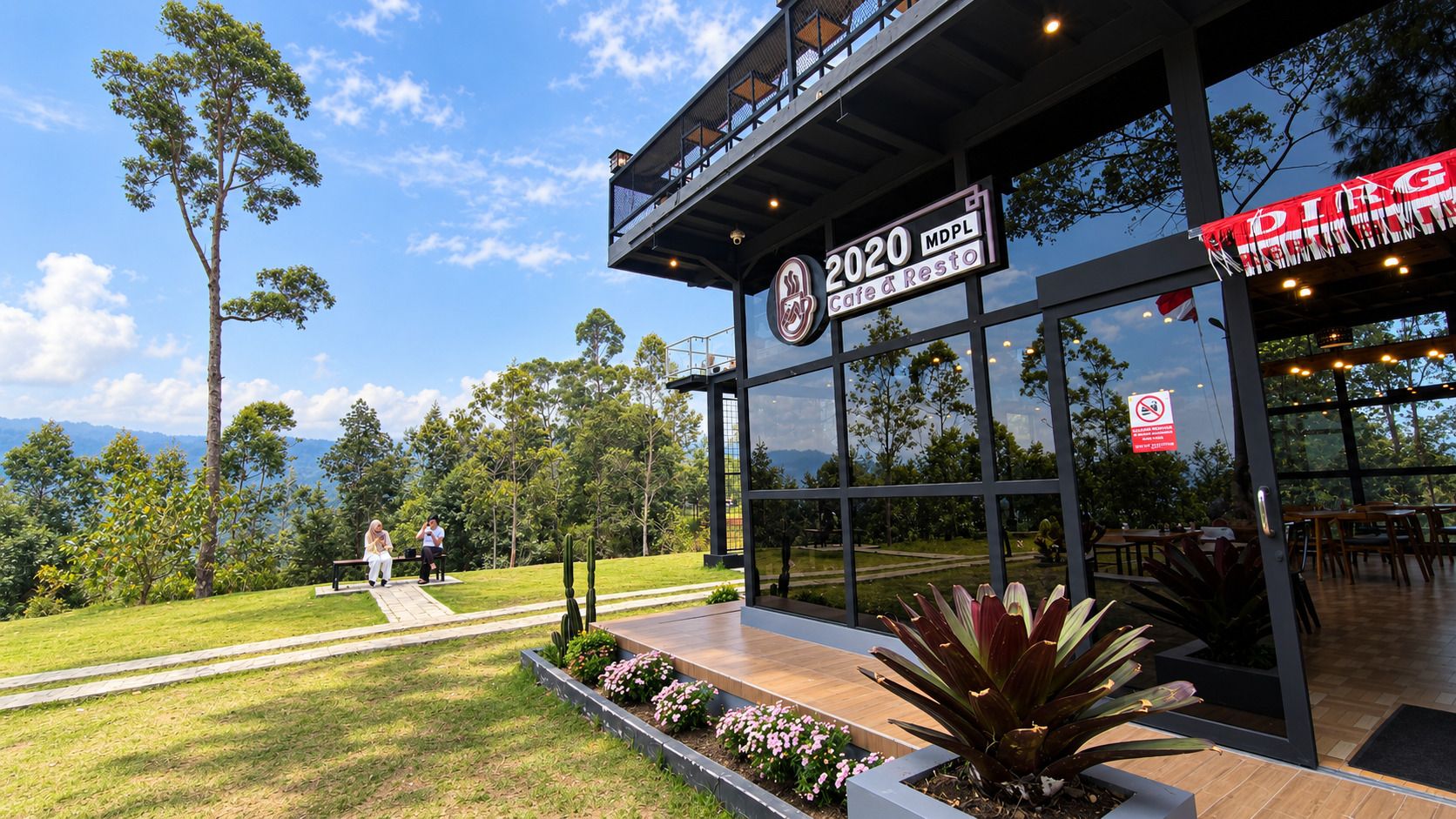 A modern building with a glass facade, outdoor seating area, and a sign indicating '2020 MDPL Cafe & Resto'.