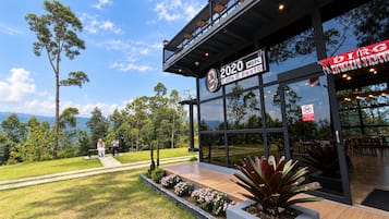 A modern building with a glass facade, outdoor seating area, and a sign indicating '2020 MDPL Cafe & Resto'.