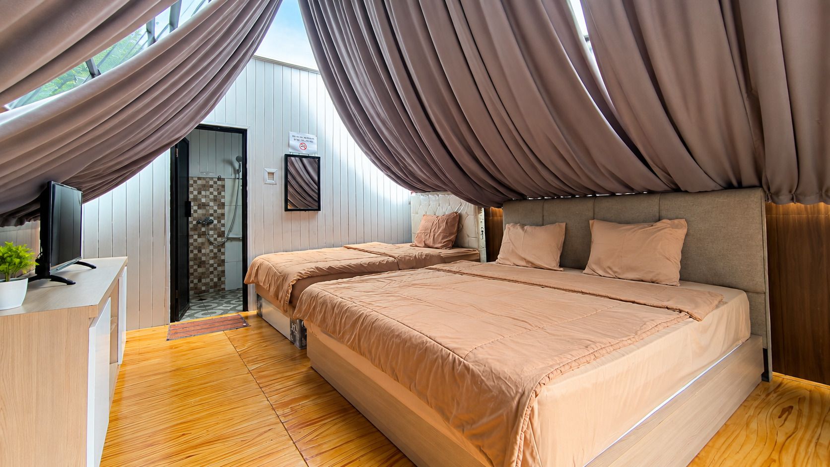 A bedroom with a bed, a desk, and a television.
