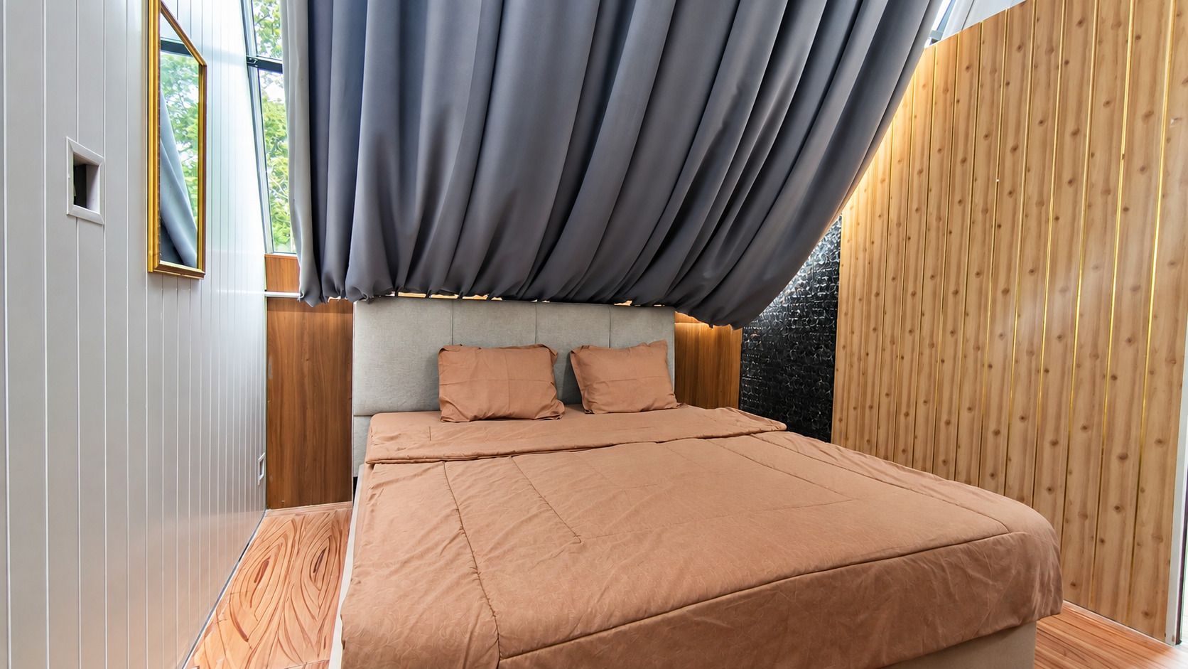 Un dormitorio con cama, almohadas, cabecero y ventana con cortinas.