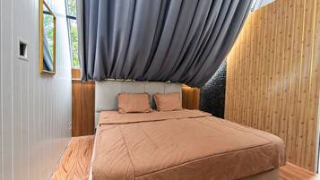 Un dormitorio con cama, almohadas, cabecero y ventana con cortinas.