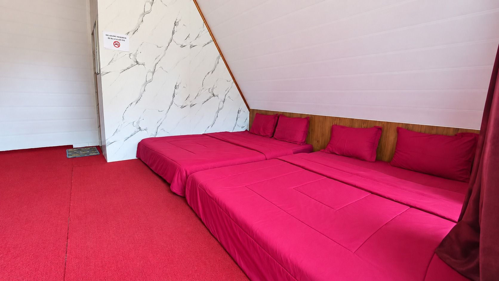 A room with a bed, red carpet, wooden headboard, and a marble-patterned wall.