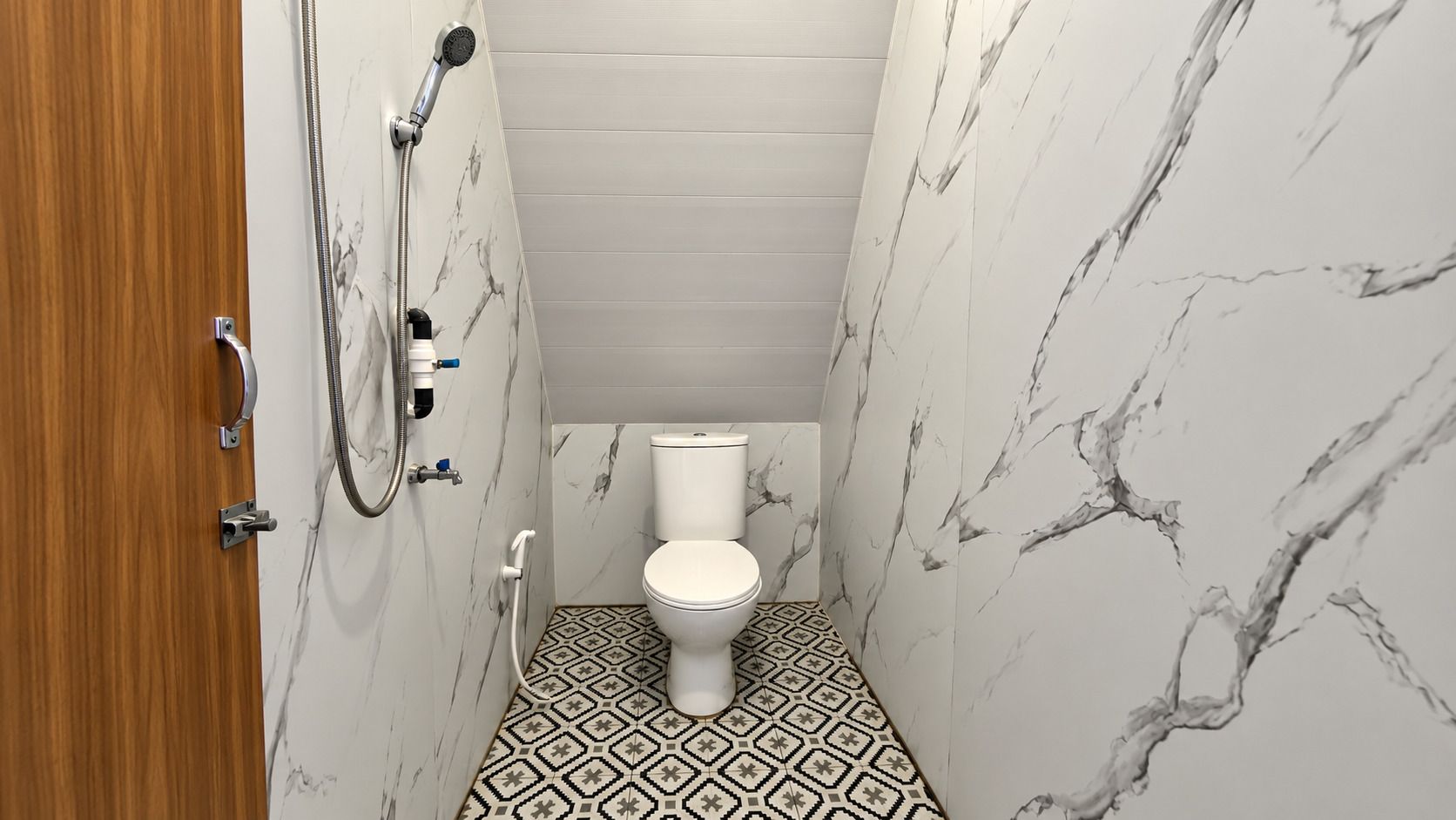 A bathroom with a toilet, shower, and a patterned floor.