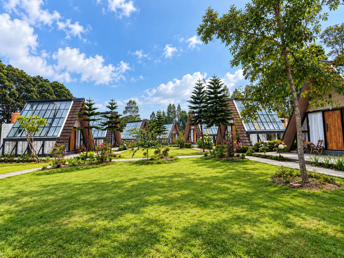 A row of modern, glass-roofed cabins with a well-maintained lawn and trees.