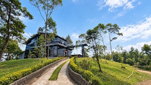 A modern building with a glass facade, surrounded by a landscaped garden with a pathway leading to it. - Sakura Hills (Tawangmangu)