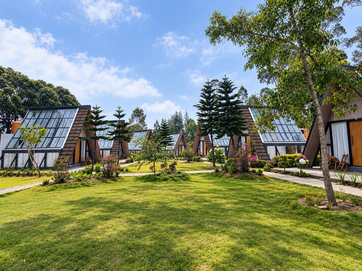 A row of modern, triangular-roofed cabins with large windows, surrounded by well-maintained lawns and trees.
