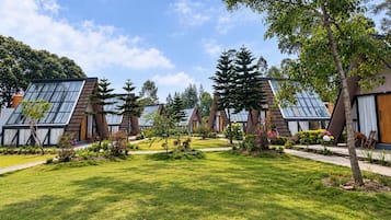 A row of modern, triangular-roofed cabins with large windows, surrounded by well-maintained lawns and trees.