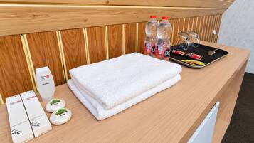A hotel reception area with a wooden panel wall, a white towel, a dental kit, and two bottles of water.